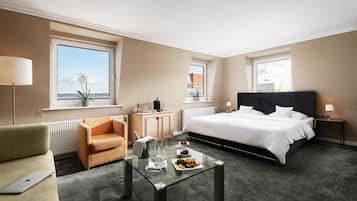Een hotelkamer met een bed, een bank, een eettafel met eten, een bureau en een raam met uitzicht.