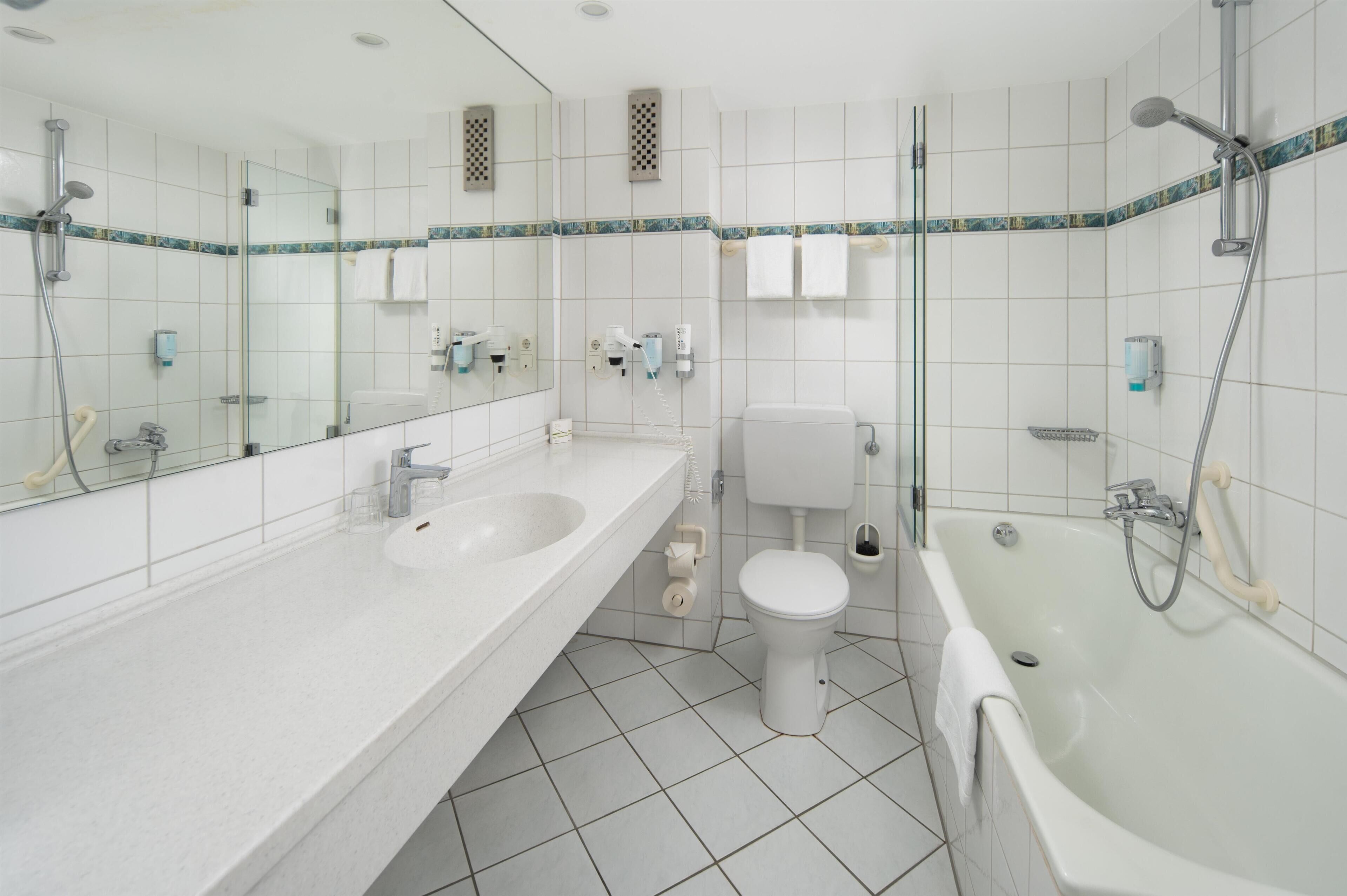 A modern bathroom with two sinks, a toilet, a bathtub, and a glass-enclosed shower.