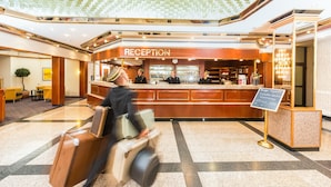 Une salle d’attente avec un panneau indiquant un délai d’attente de 15 minutes et des frais de 10 euros.