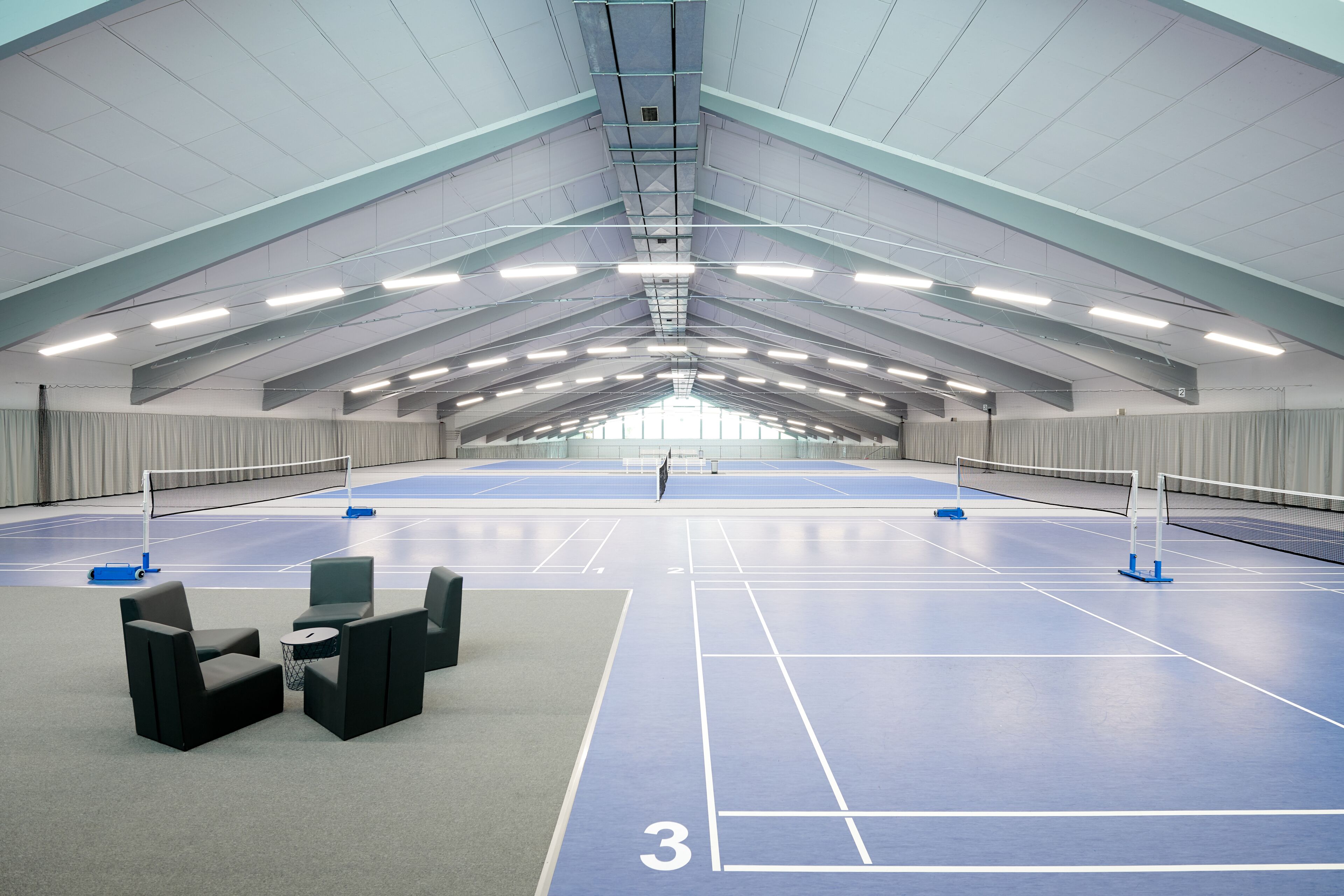 An indoor tennis court with seating and a net.