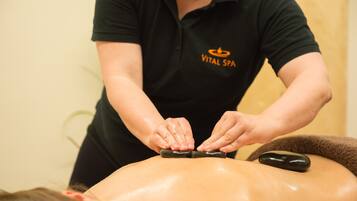 Eine Person erhält eine Rückenmassage mit einem Stein.