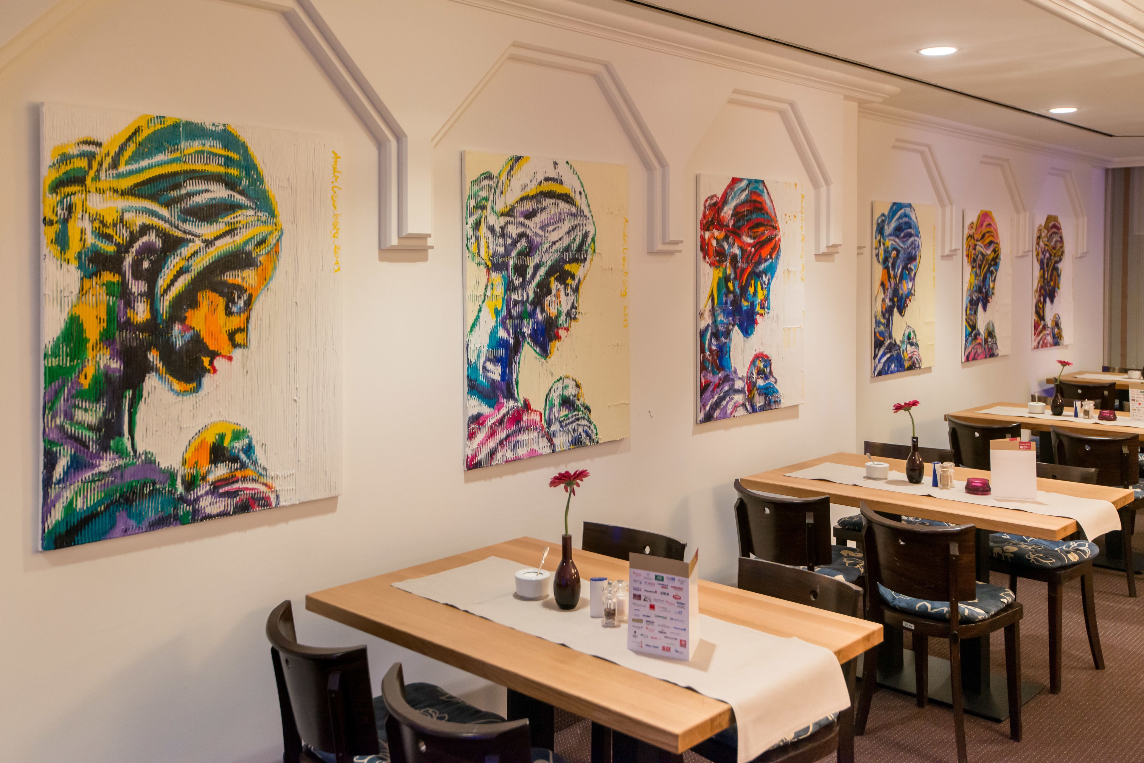 Un ristorante con tavoli e sedie, e dipinti colorati alle pareti.