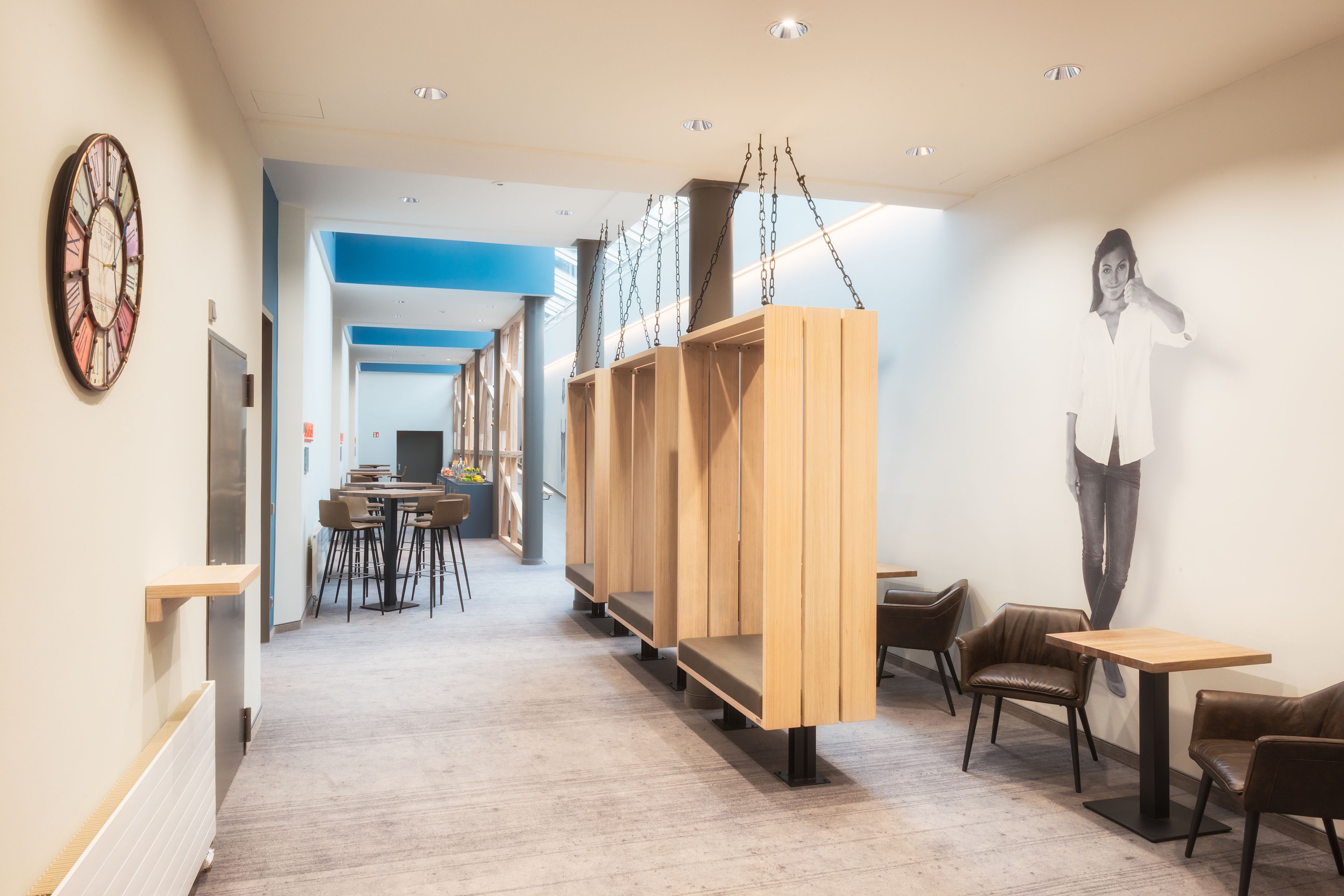 A modern interior with a long hallway, wooden seating areas, and a dining space.