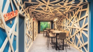 Un intérieur moderne avec un plafond en bois au design géométrique, une enseigne bien visible indiquant « SALON 33 », et une rangée de tables et de chaises.