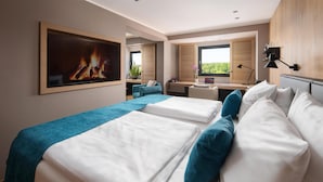 A hotel room with two beds, a desk, a chair, a TV, and a window with a view.