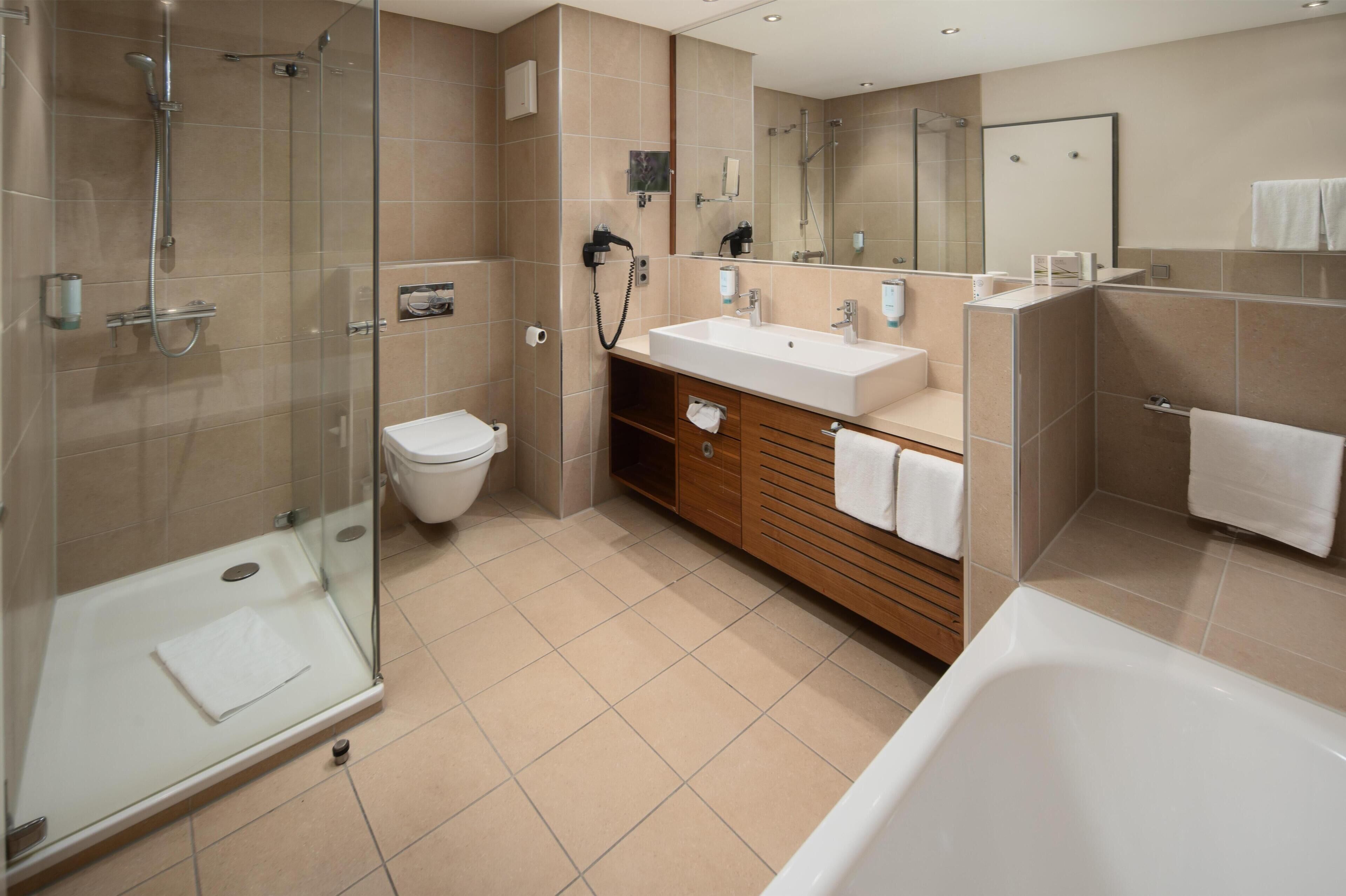 A modern bathroom with a glass-enclosed shower, a white sink, and a bathtub.