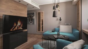 Un salon moderne avec un téléviseur à écran plat, un canapé, une table basse et une cheminée.