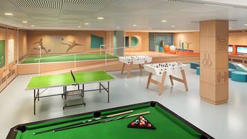 Un espacio recreativo con mesa de ping pong, mesa de billar y mesa de futbolín.