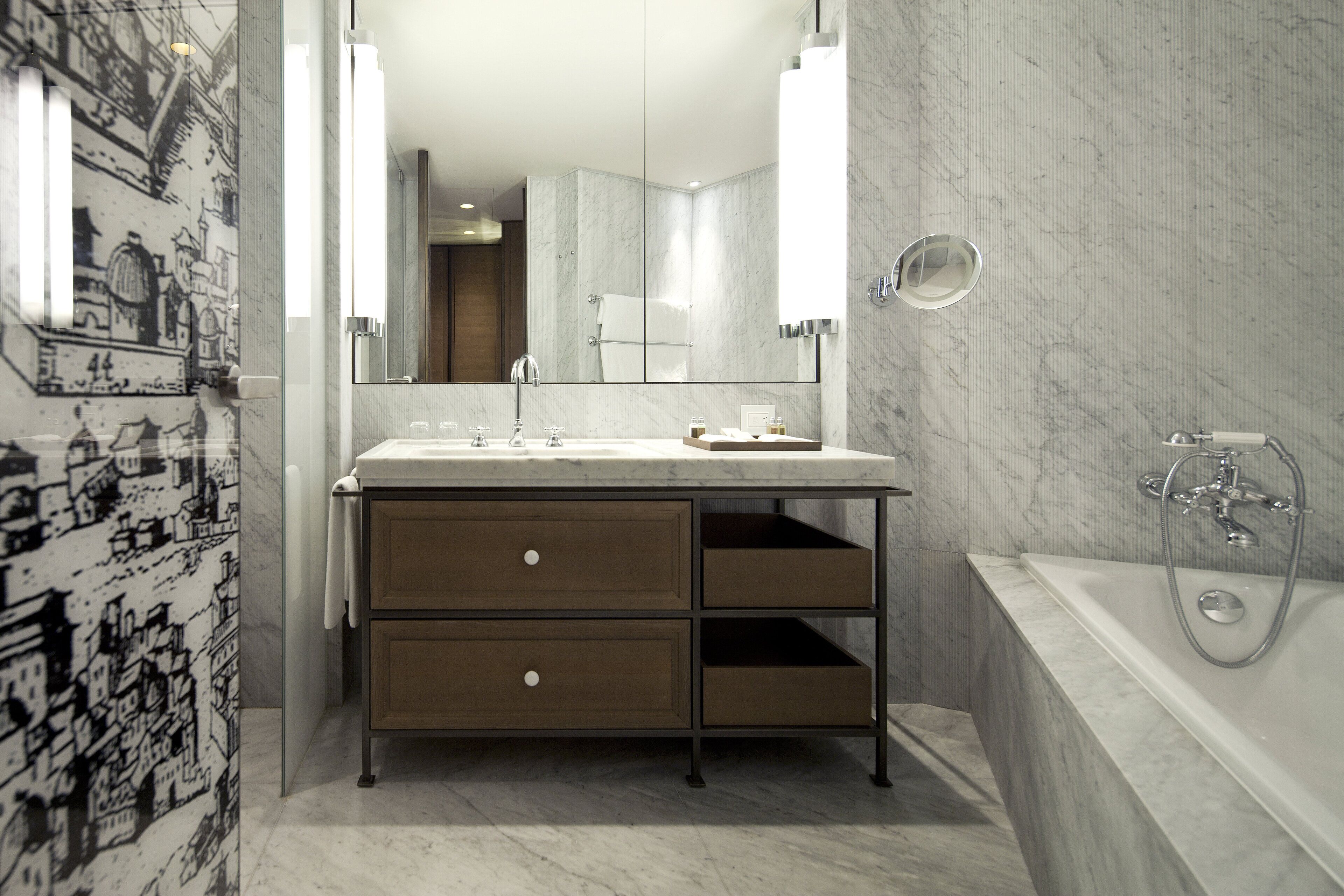 A modern bathroom with a marble vanity, a large mirror, and a separate shower area.