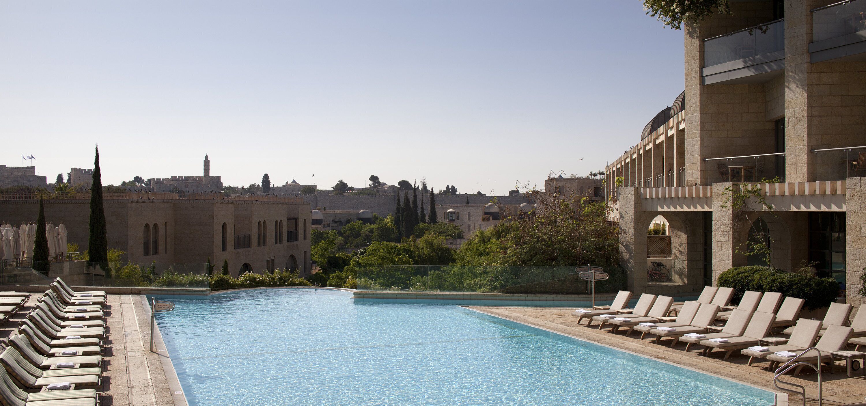 A pool area with lounge chairs and a view of historic buildings in the background.