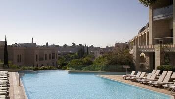 A pool area with lounge chairs and a view of historic buildings in the background.
