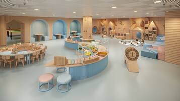 Children can play on a large horse, a circular table, and small tables and chairs in this play area with wooden panels and arches.