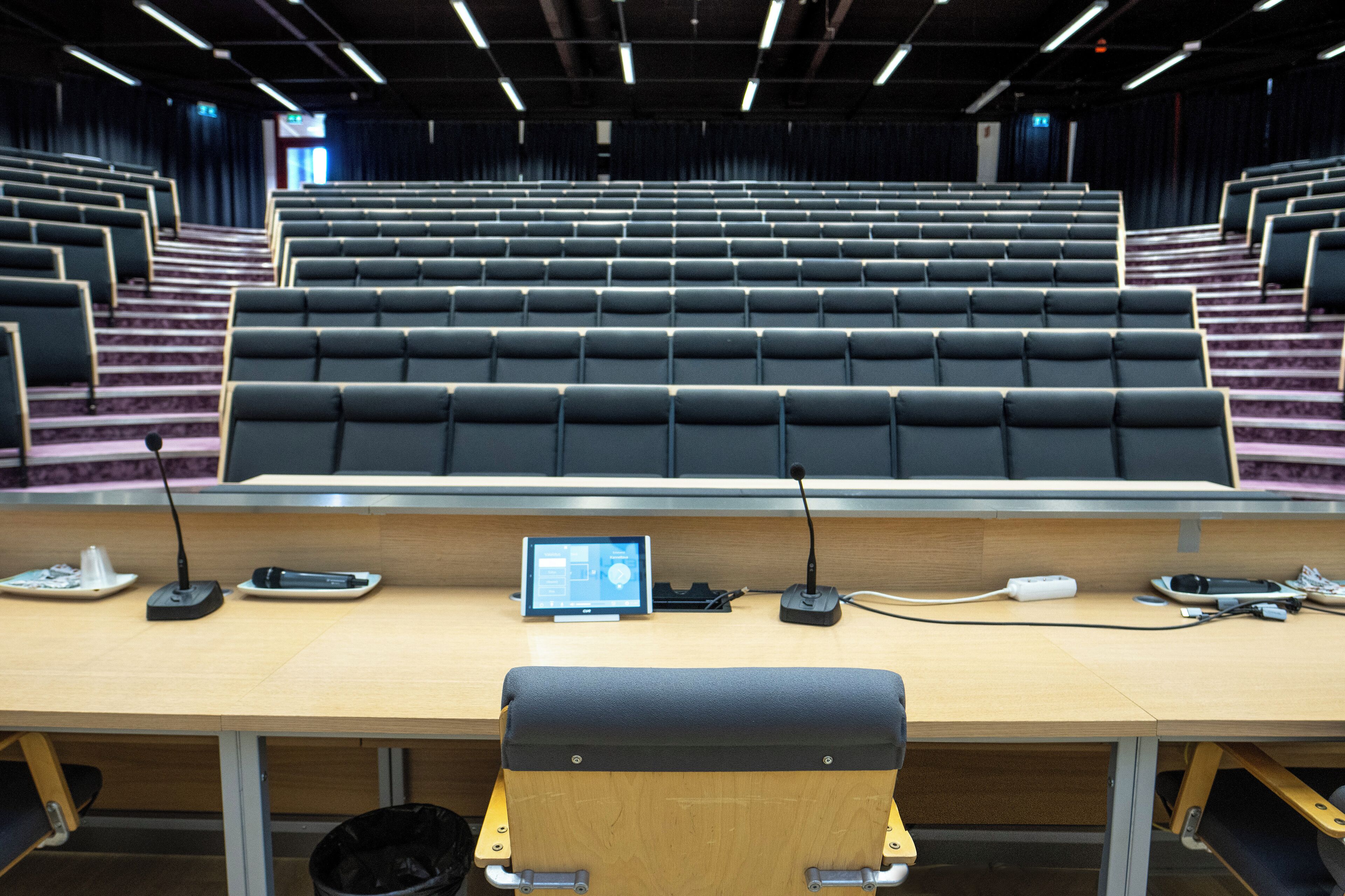 Un salón de conferencias con filas de sillas, un atril, una computadora portátil y un proyector.