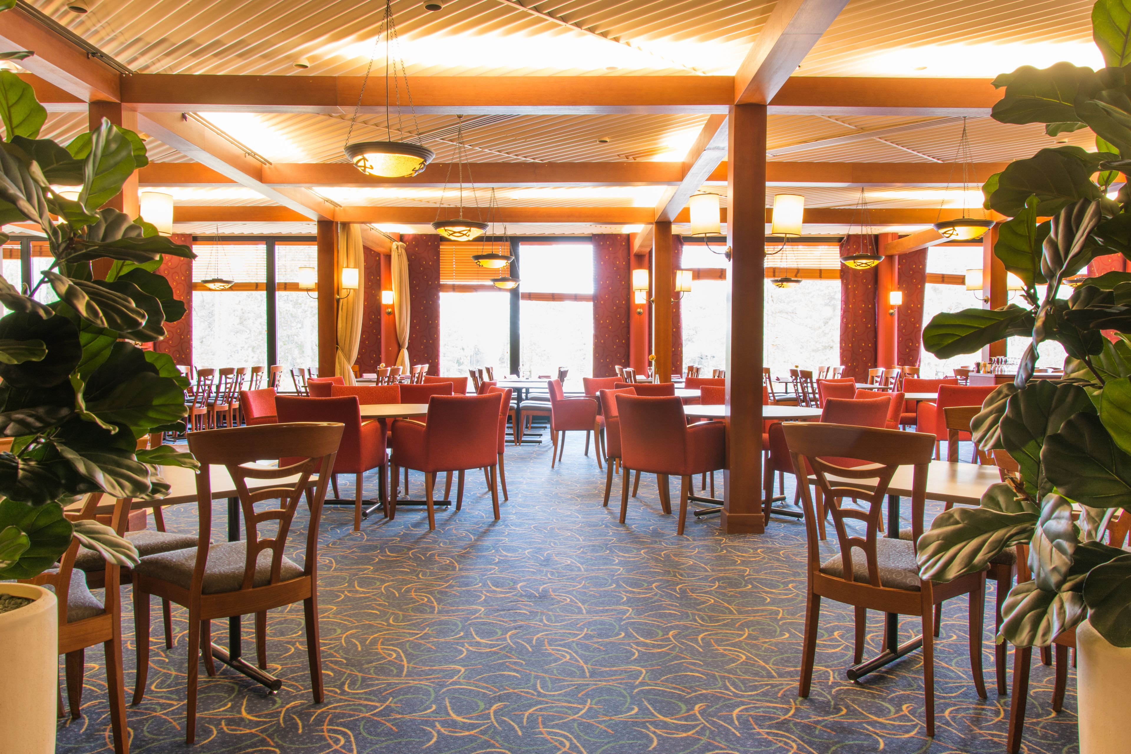 Un restaurante espacioso con techos altos, ventanas grandes y una alfombra estampada.