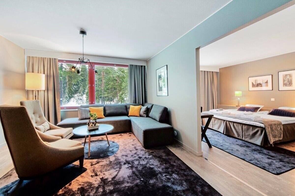 Moderni hotellihuone, jossa on sohva, nojatuoli ja sänky.