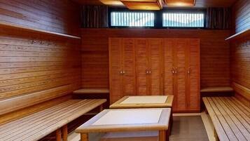 A sauna room with wooden benches, a central table, and a window at the far end.