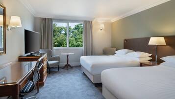 A hotel room with two beds, a desk with a chair, a television, and a window with curtains.