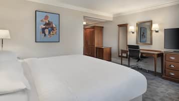 Una habitación de hotel con una cama grande, un escritorio con una silla, un televisor y un armario.