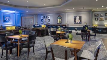 A hotel lobby with multiple seating areas, framed artwork on the walls, and a large mirror.