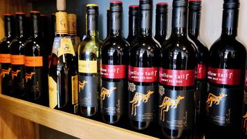 Ein Regal mit verschiedenen Weinflaschen, einige beschriftet mit 'Yellow Tail' und andere mit 'Jammy Red Roo'.