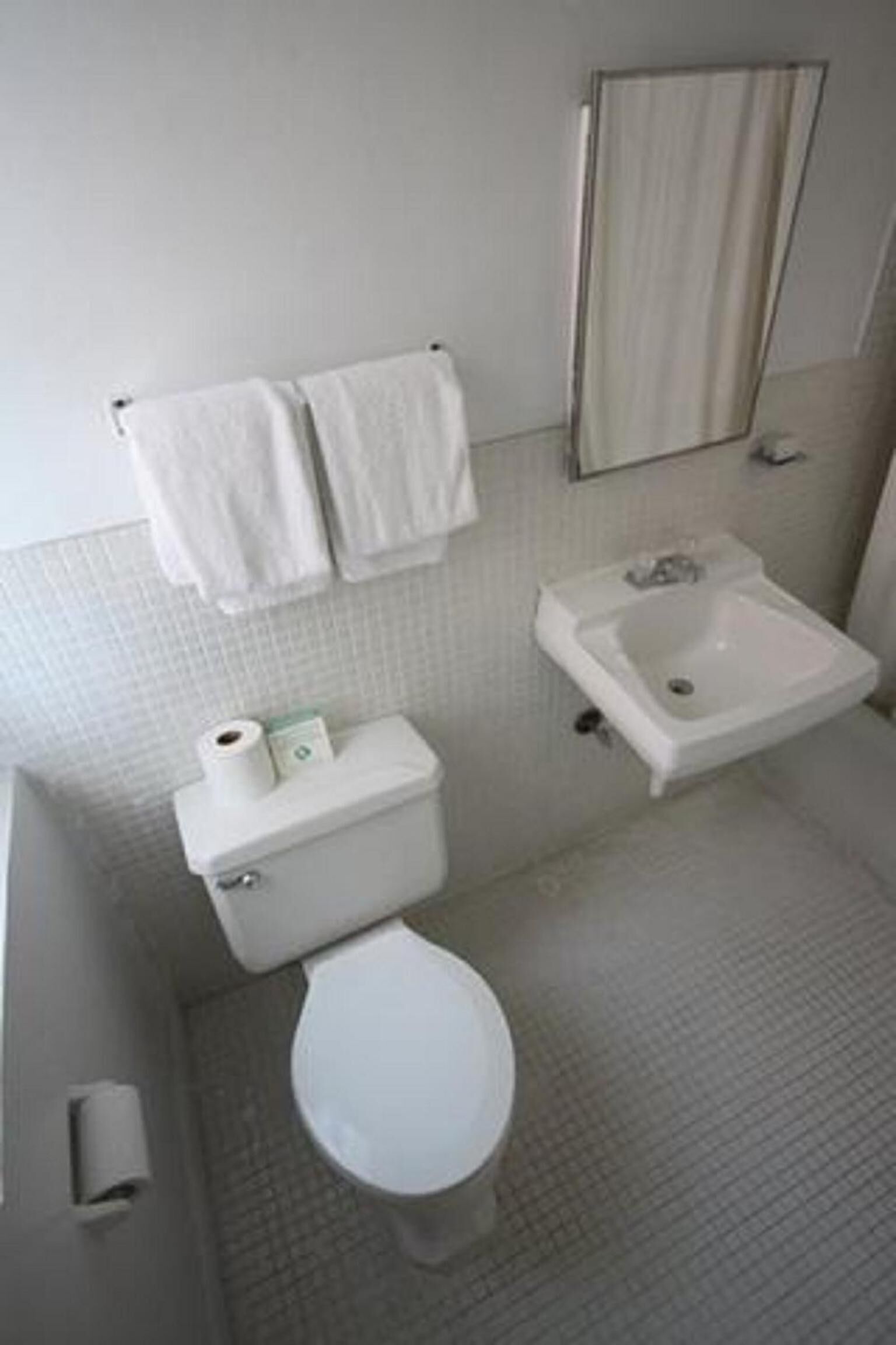 Ein kleines Badezimmer mit Toilette, Waschbecken und zwei Handtüchern, die an der Wand hängen.