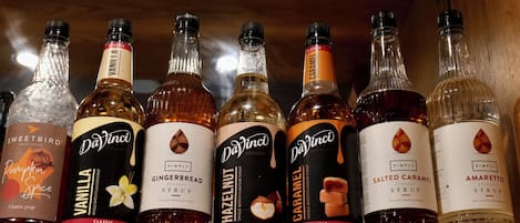 Une étagère contenant différentes bouteilles de sirop, notamment aux saveurs vanille, pain d’épices, noisette, caramel, caramel au sel et amaretto.