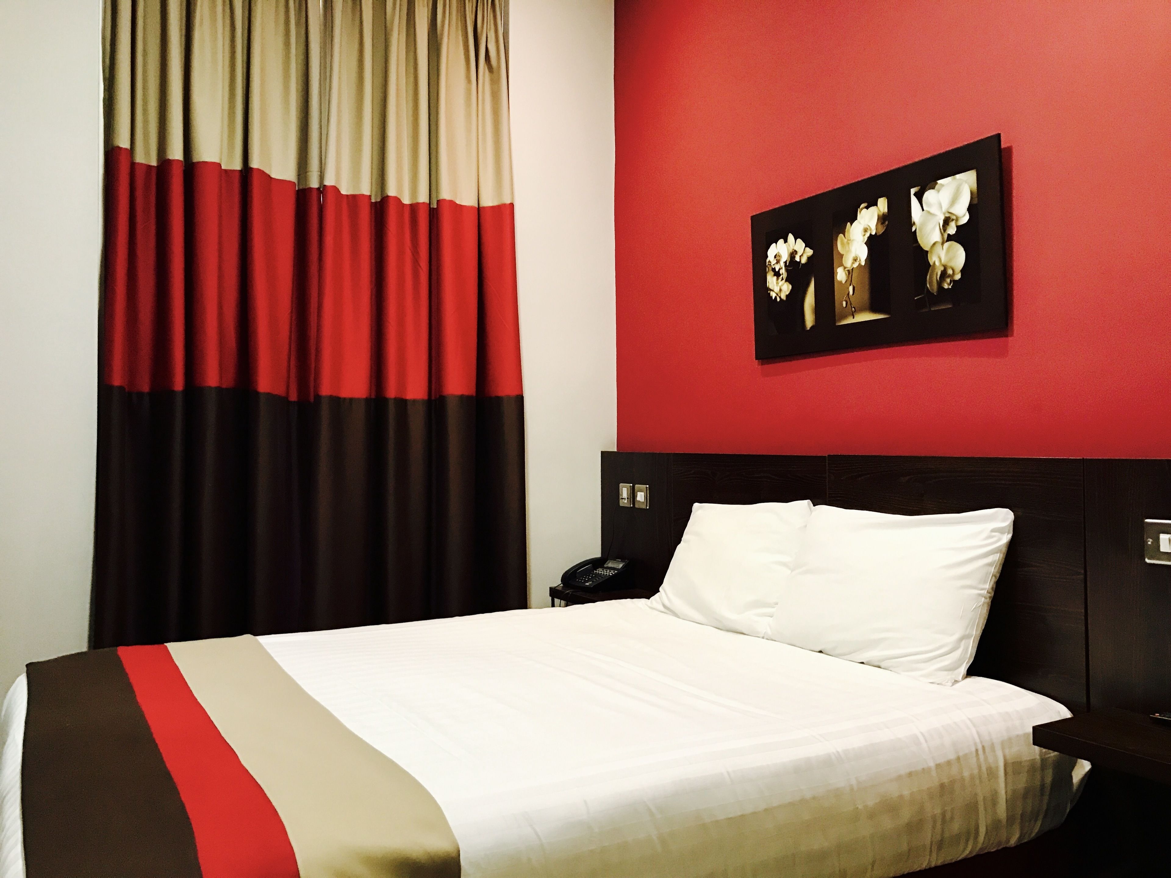Habitación de hotel con una cama, mesita de noche, teléfono y un cuadro en la pared.