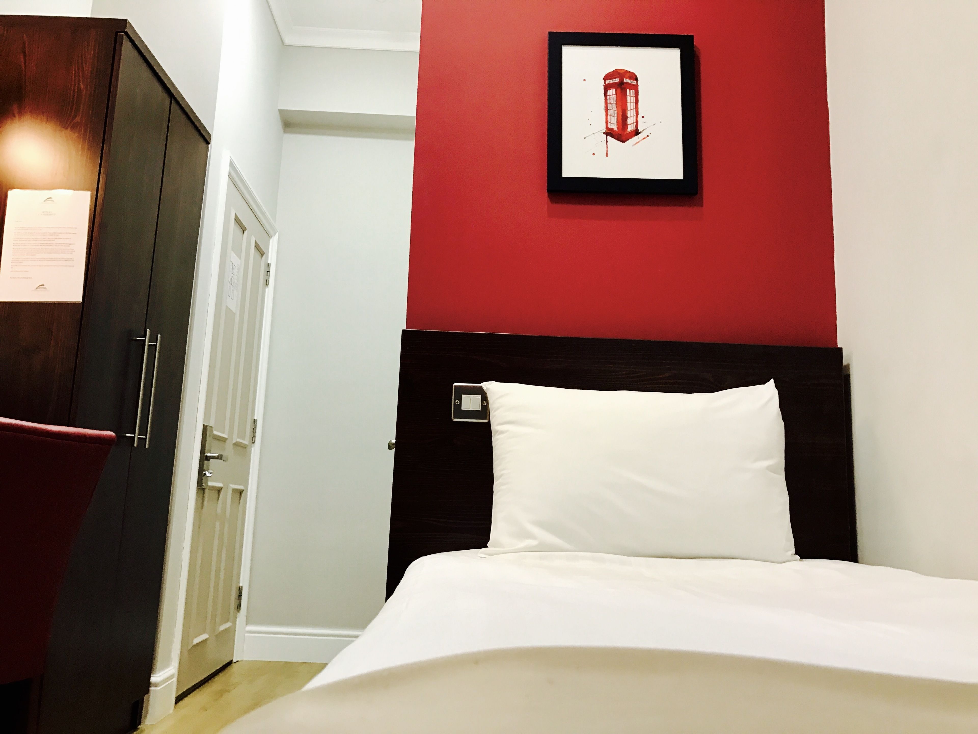 Una habitación de hotel con una cama, un armario y un cuadro en la pared.