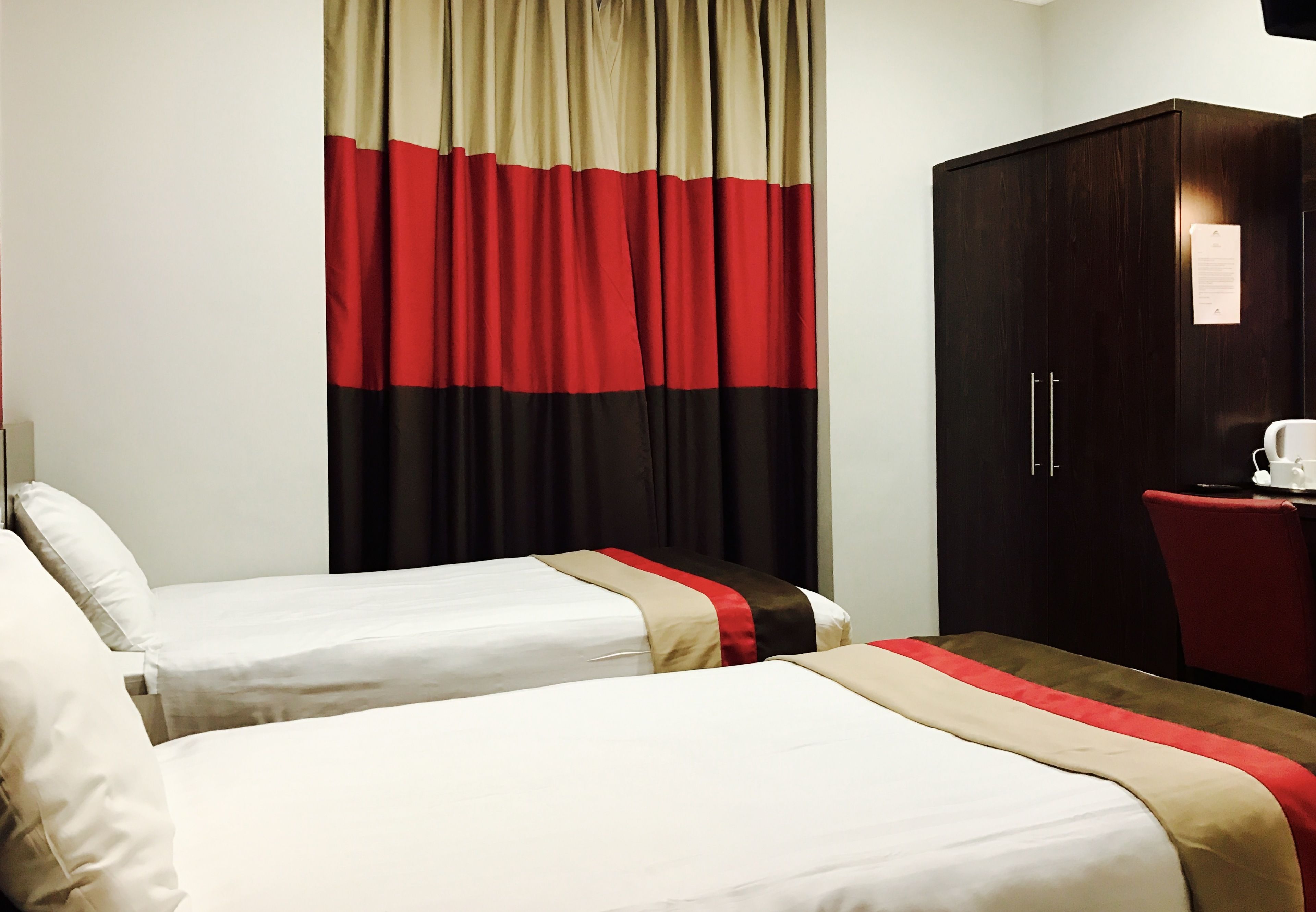 Een hotelkamer met twee bedden, een kledingkast en een bureau met een stoel.