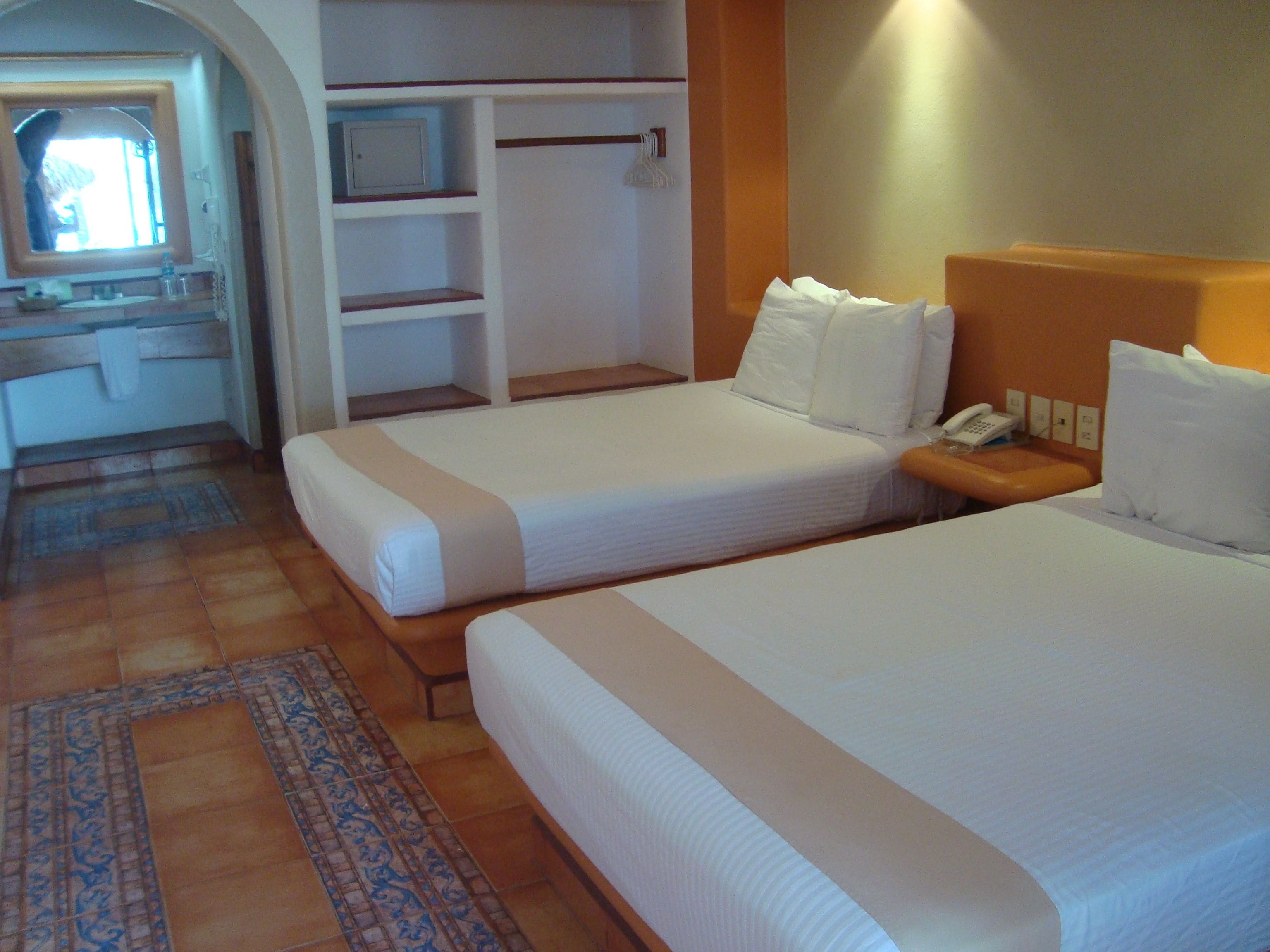 Una camera d'albergo con due letti, bagno e un angolo cottura.