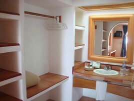 Un baño con tocador de madera, un lavabo, un espejo y un perchero para toallas.