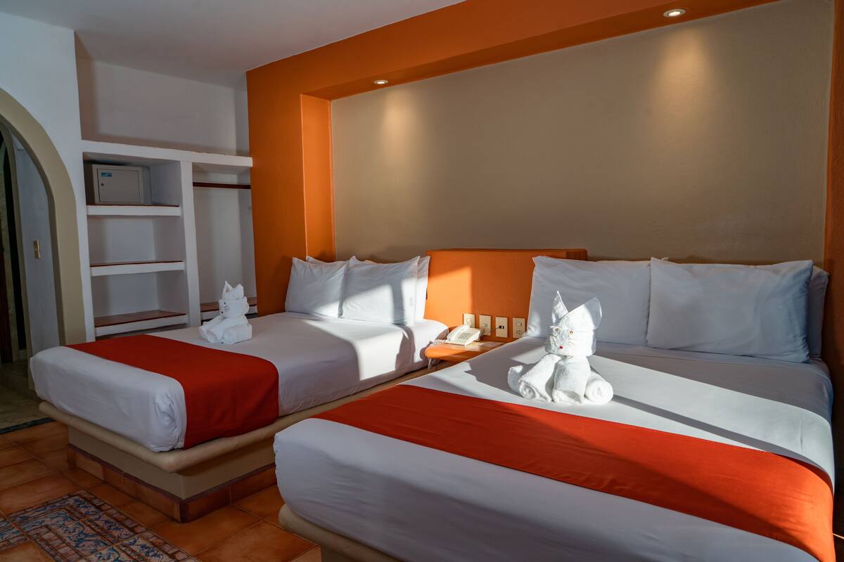 Een hotelkamer met twee bedden, een garderobe en een klein bureau met telefoon.