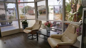 A corner seating area with two leather chairs and a small table, a potted plant, and a vase with flowers. - Country Motor Inn Singleton (Singleton)