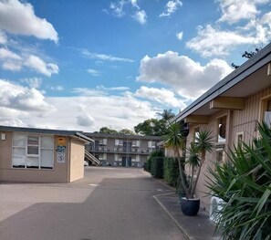 A building with a parking lot, a small structure with a sign, and a clear sky.