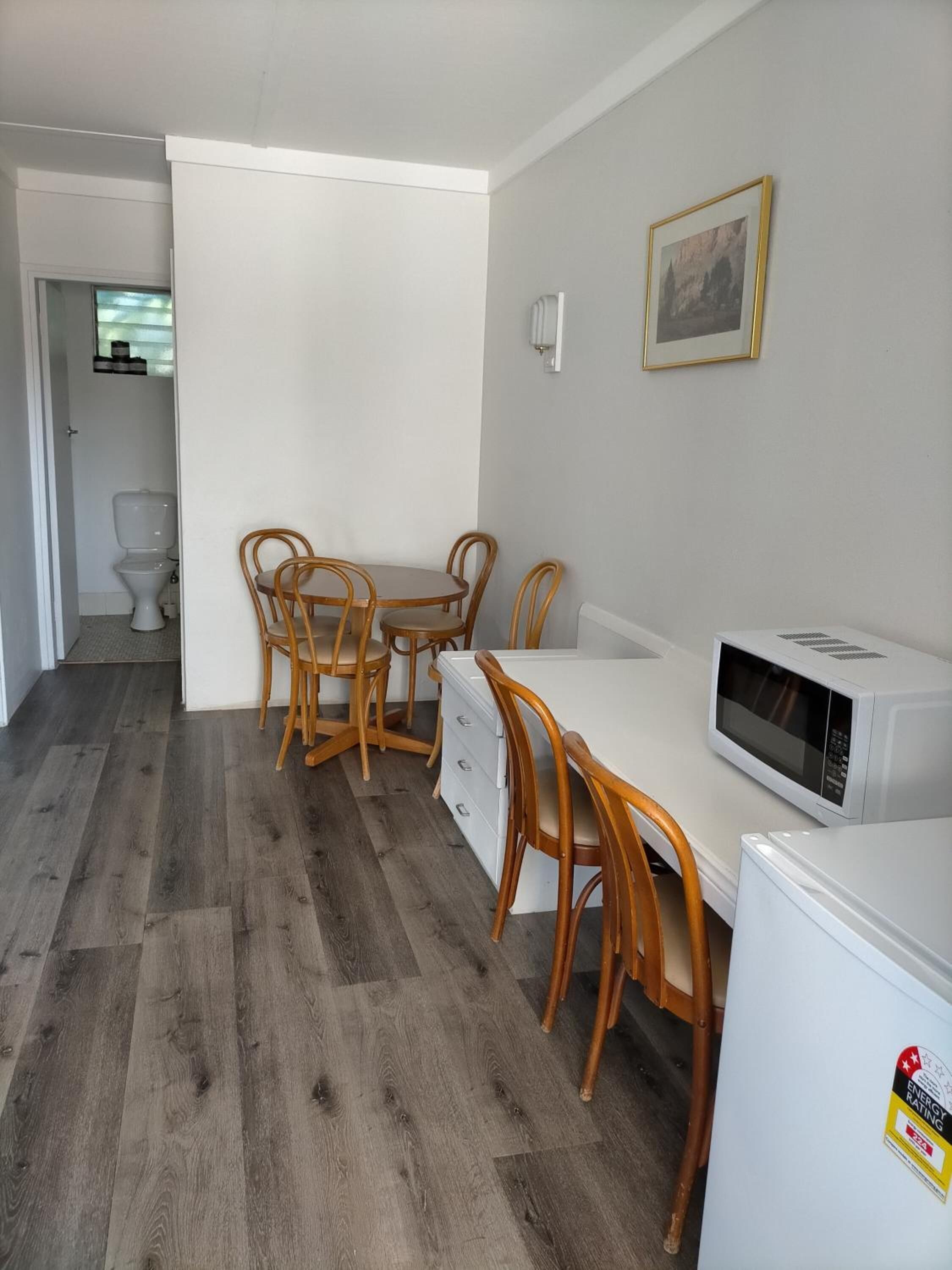 Una cocina compacta con encimera blanca, microondas y refrigerador.
