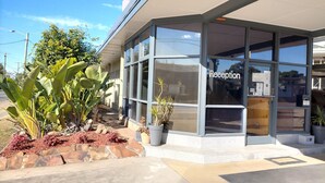 A reception area with a glass facade, potted plants, and a clear sky. - Country Motor Inn Singleton (Singleton)