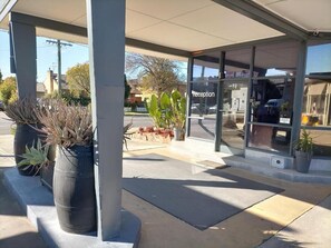 A reception area with a glass door, potted plants, and a clear view of the street outside.