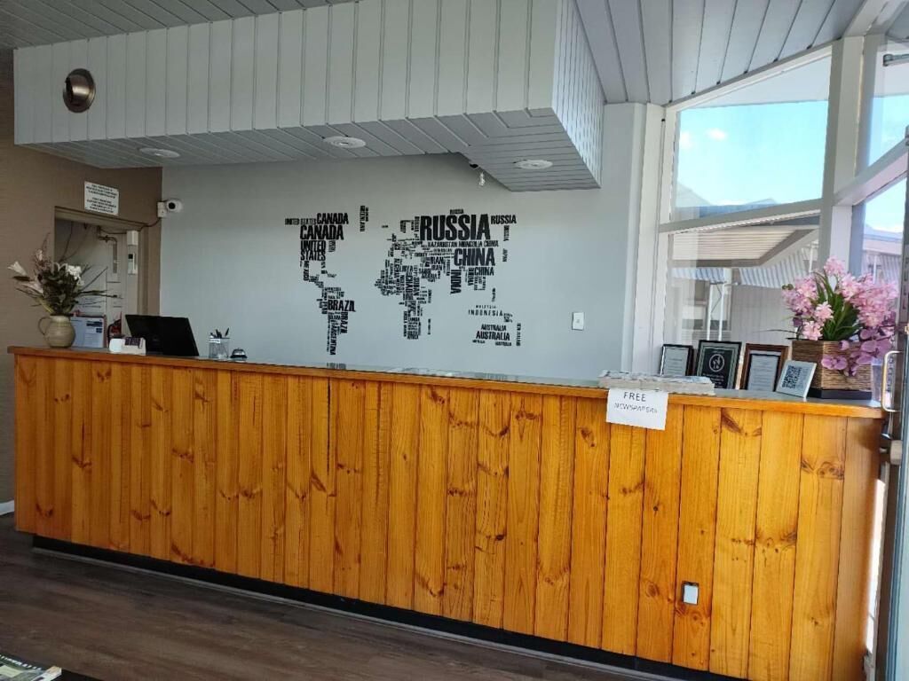 A reception desk with a world map wall art, a wooden counter, and a sign indicating free Wi-Fi.
