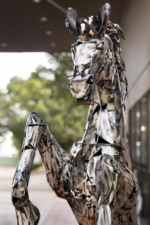 Une sculpture métallique représentant un cheval, placée dans un espace extérieur.