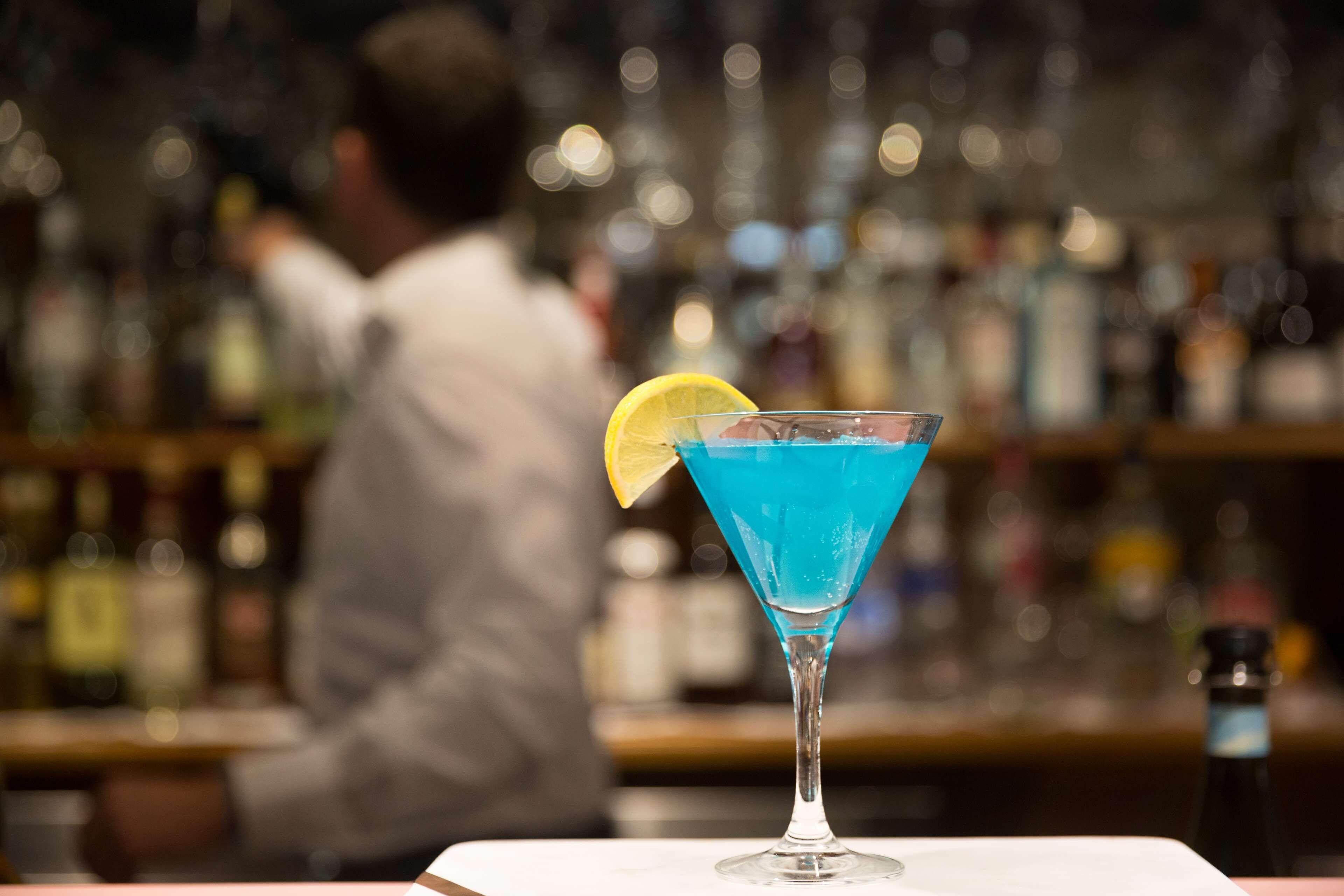 Un bar, avec un cocktail servi dans un verre à martini, décoré d’une tranche de citron.