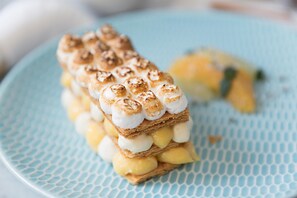 Un dessert composé de couches de gâteau et de guimauves, présenté sur une assiette bleue.