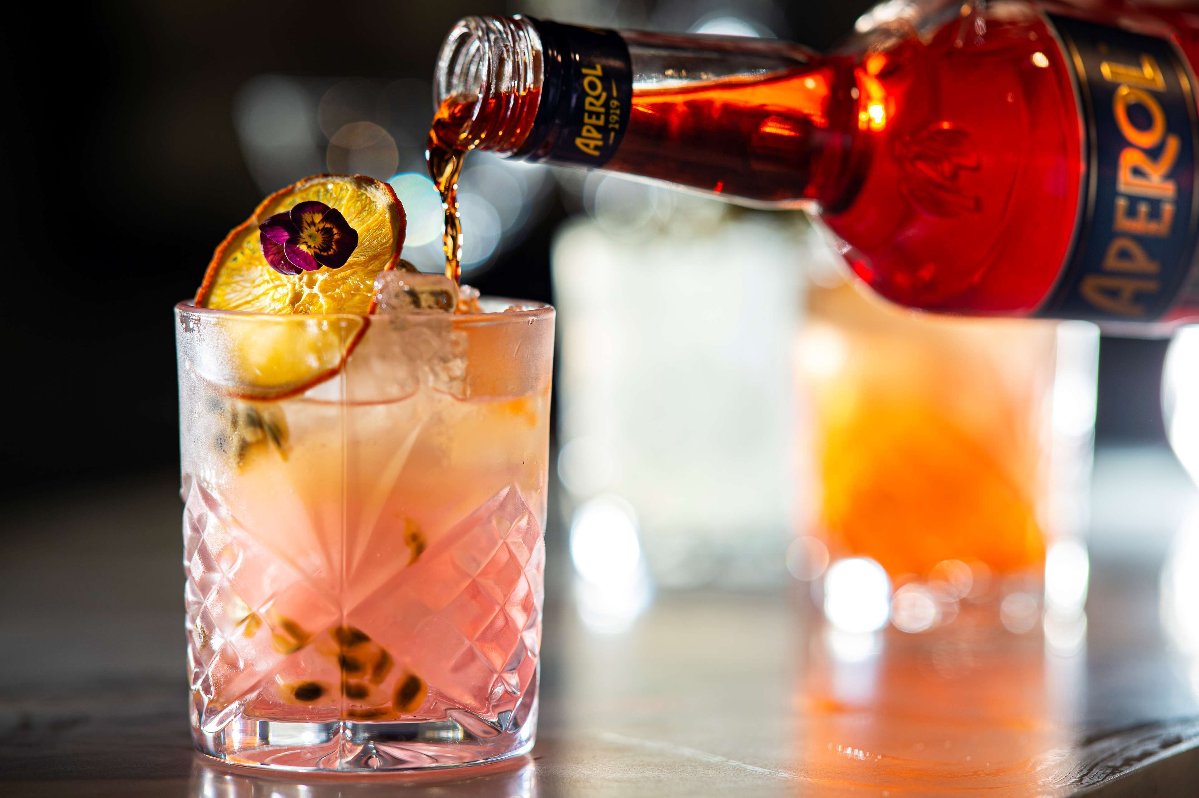 A cocktail being poured into a glass with a decorative garnish.