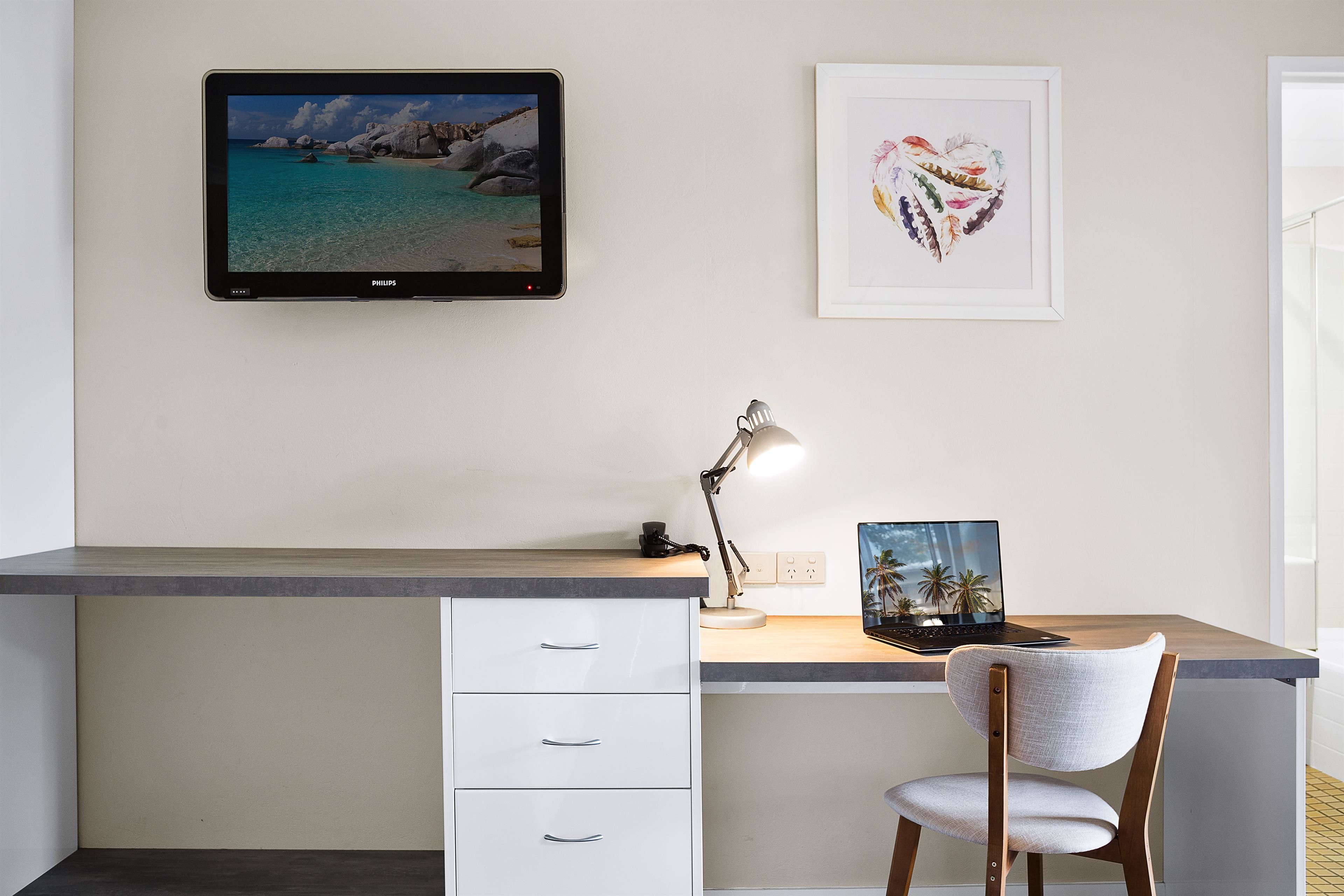 A modern office desk with a computer, a chair, and a desk lamp.