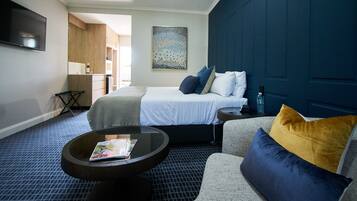A hotel room with a bed, a round coffee table, a sofa, and a TV mounted on the wall.