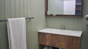 A bathroom with a wooden vanity, a white sink, and a towel hanging on a metal towel rack.