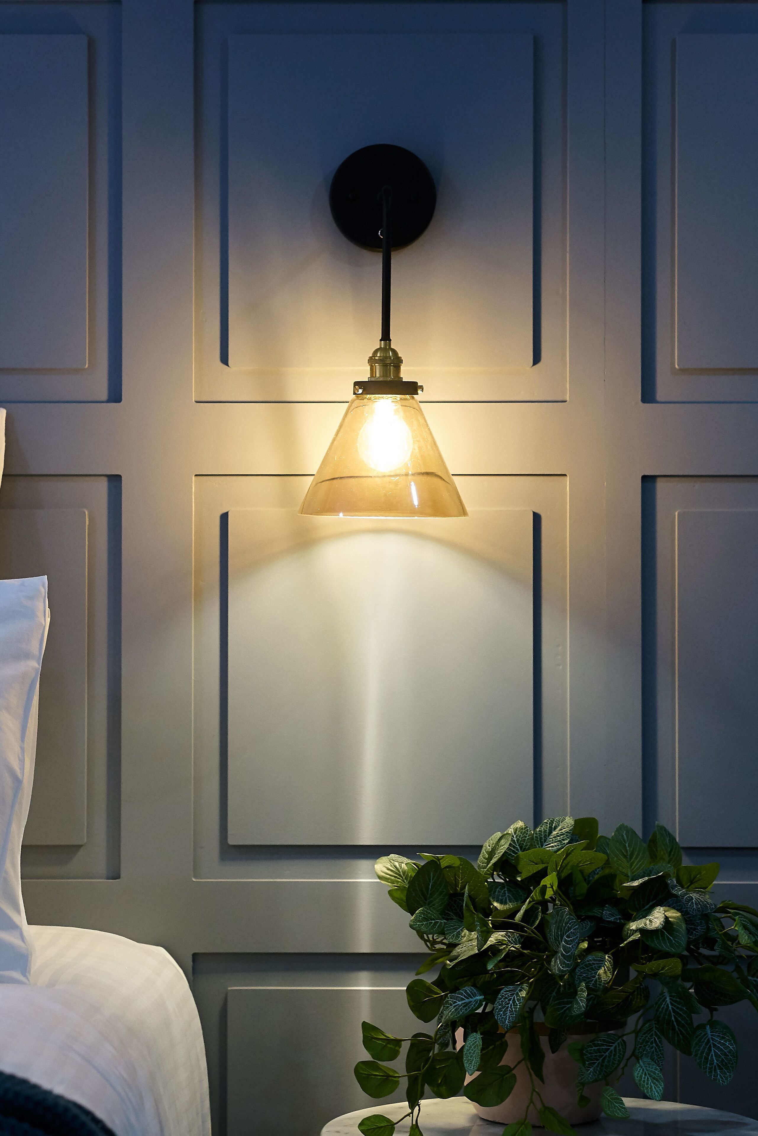 Una habitación moderna con una cama, una lámpara de pared y una planta en maceta.