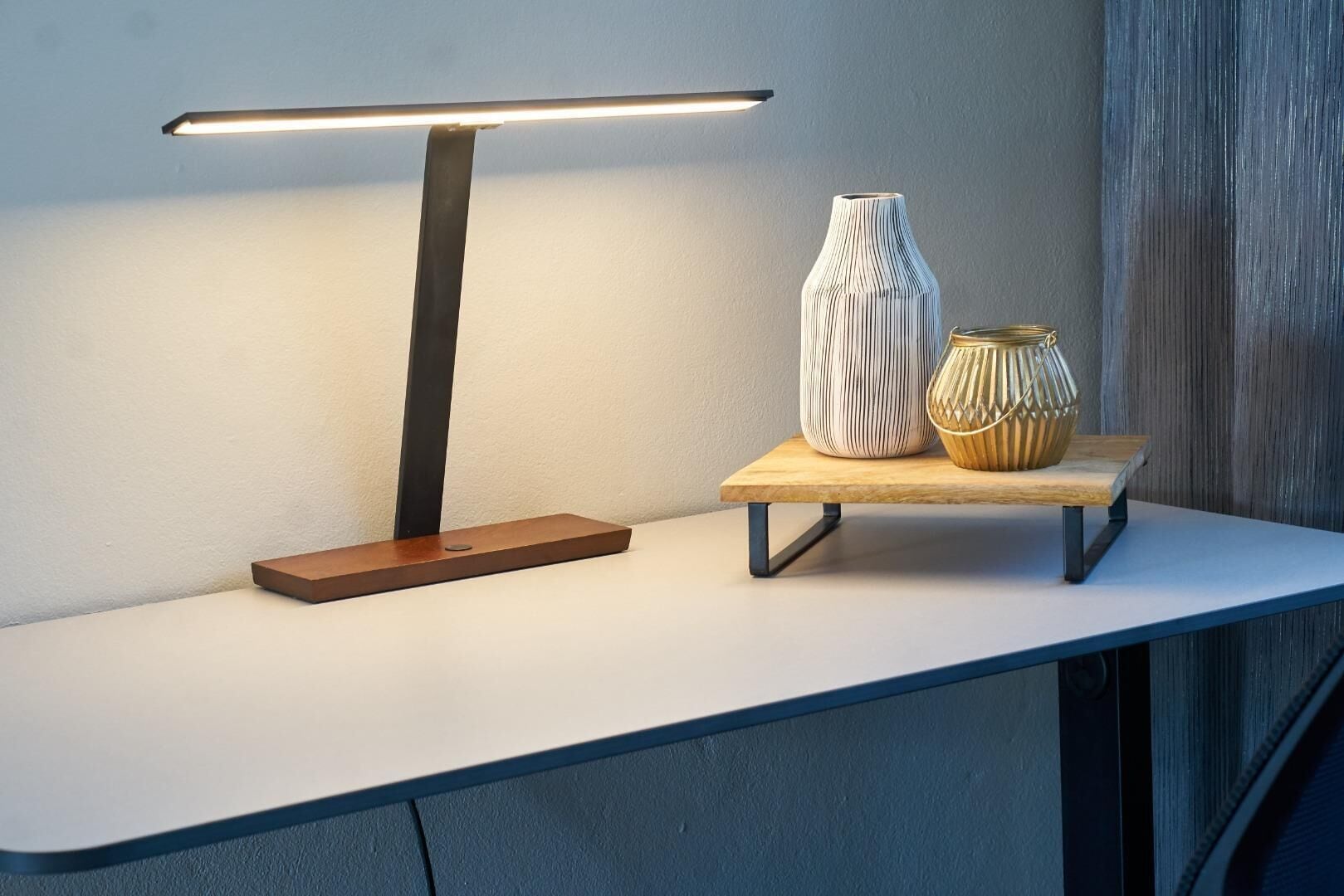 A modern table with a minimalist lamp, two decorative vases, and a wooden shelf.