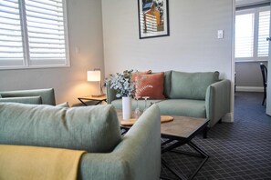 A living room with a green sofa, a wooden coffee table, and a vase with flowers. - Country Comfort Armidale (Armidale)