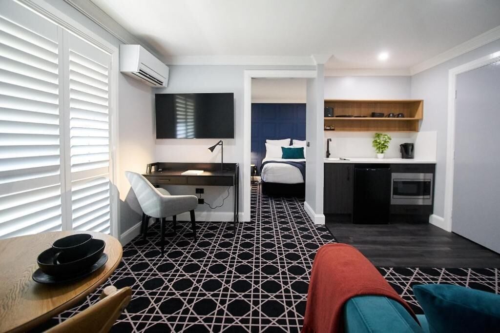 A compact living space with a kitchenette, a dining area, and a bedroom.