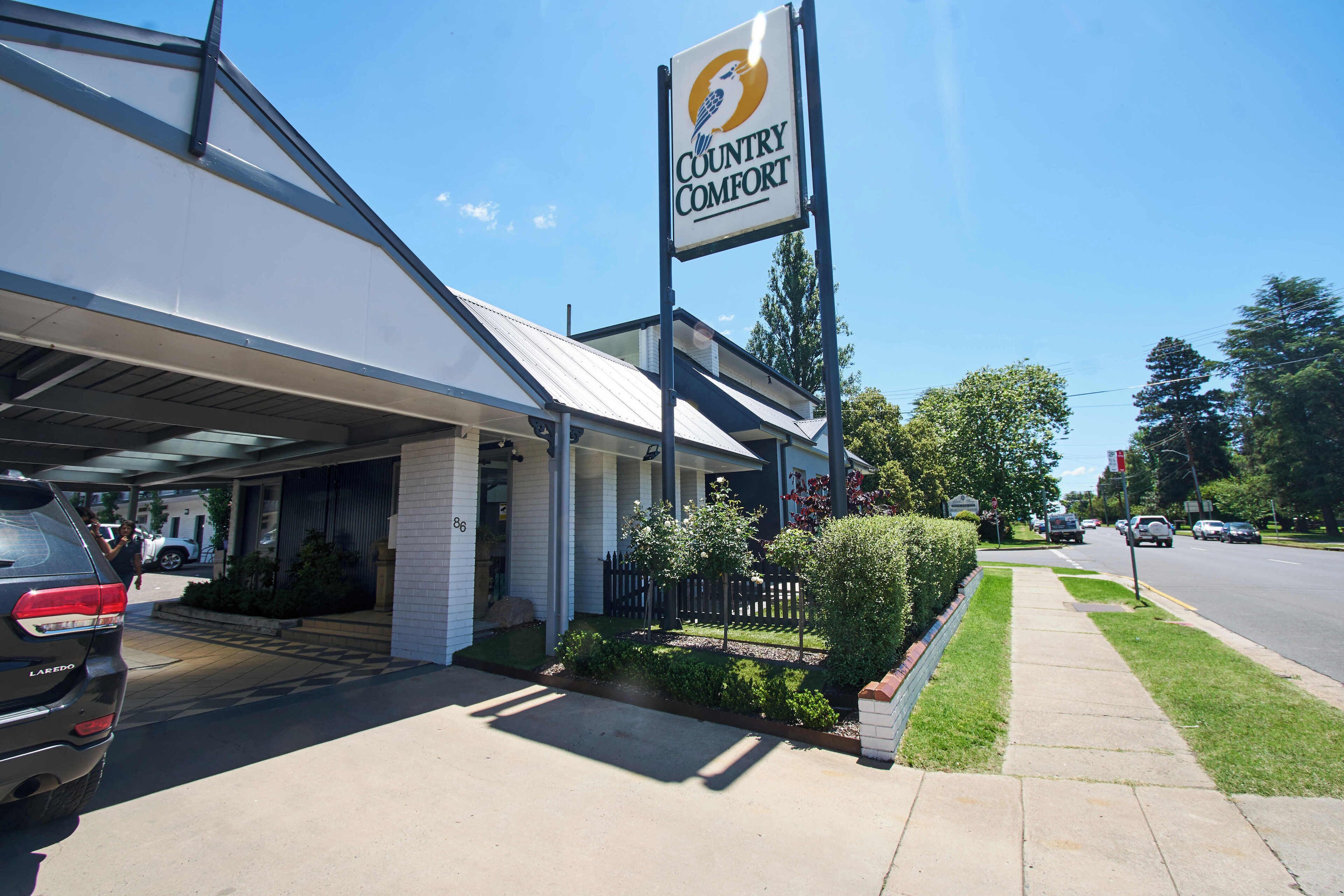 A building with a sign reading 'Country Comfort,' a covered entrance, and a paved driveway.